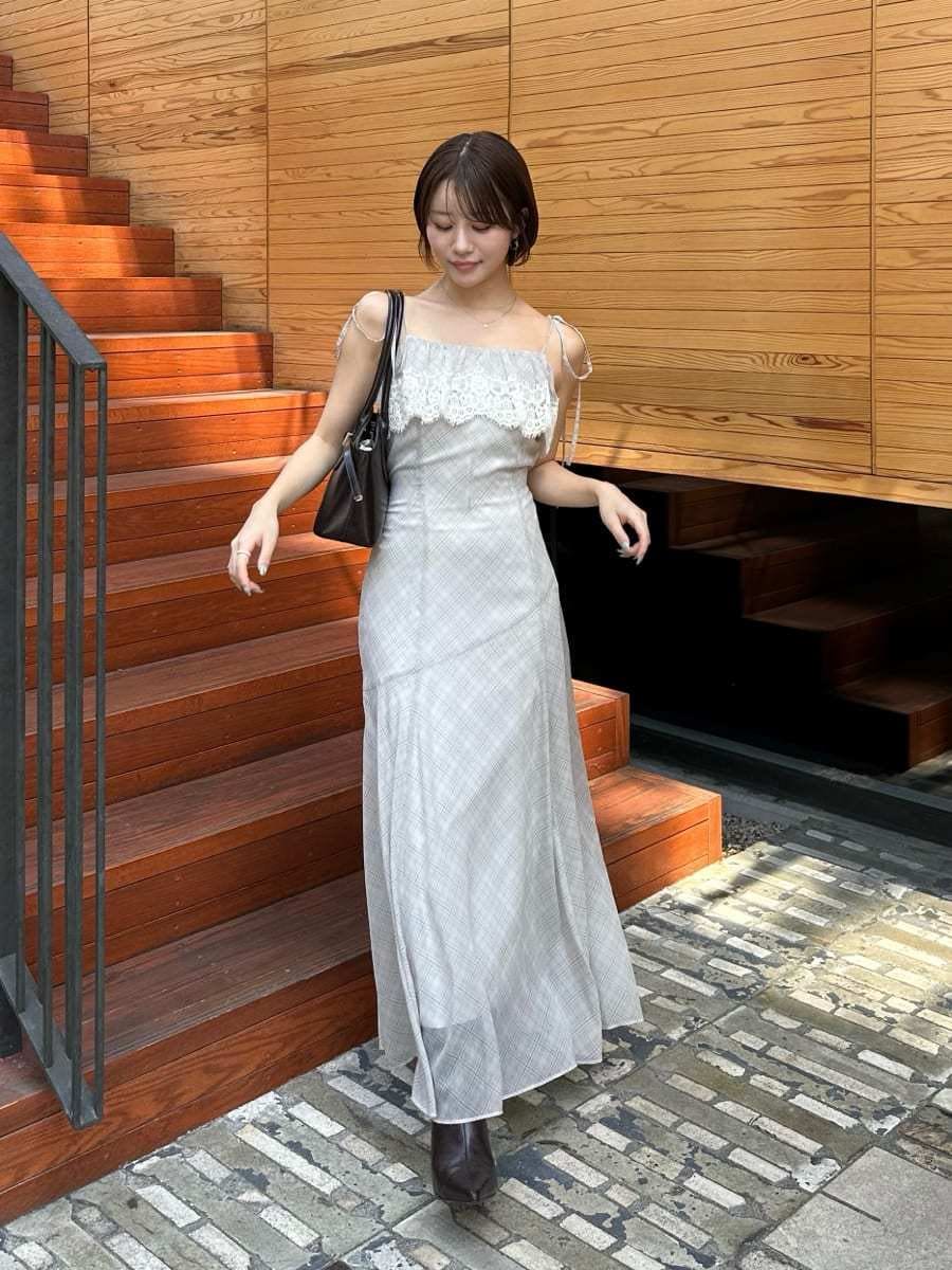 ベージュ系のワンピース、ブラウン系のブーツ、ブラウン系のボストンバッグを着用したレディースの夏コーディネートの2枚目の写真