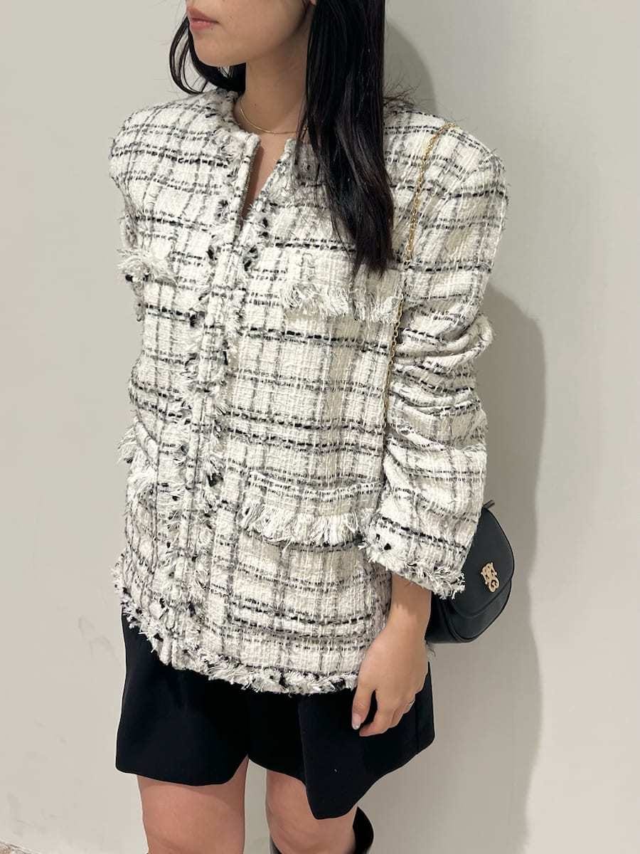 ブラウン系のブーツ、ホワイト系のノーカラージャケット、ブラック系のショルダーバッグを着用したレディースの冬コーディネートの4枚目の写真