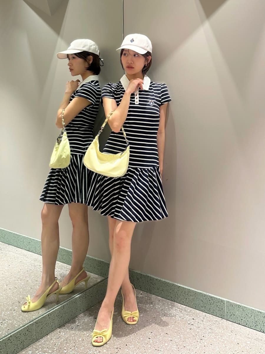 ブルー系のワンピース、イエロー系のショルダーバッグ、ホワイト系のキャップを着用したレディースの夏コーディネートの6枚目の写真