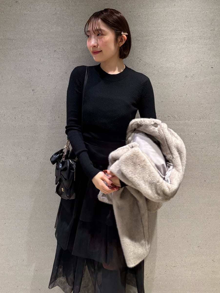 グレー系のブーツ、ベージュ系のステンカラーコート、ブラック系のスカートを着用したレディースの秋コーディネートの3枚目の写真