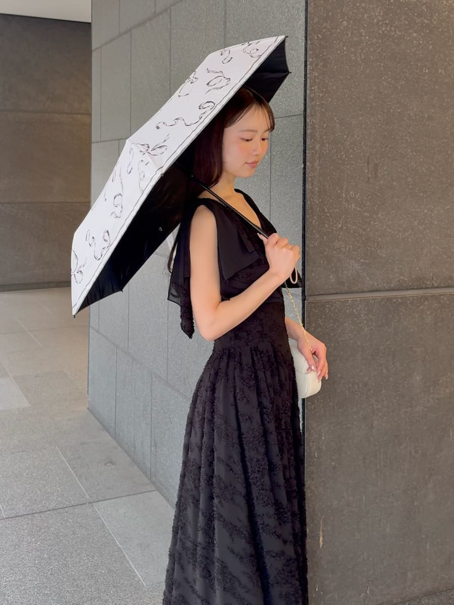 ブラック系のワンピース、ホワイト系のショルダーバッグ、ホワイト系の折りたたみ傘を着用したレディースの春コーディネートの7枚目の写真