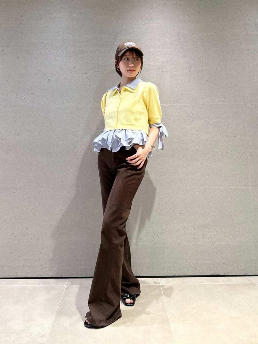 ブラック系のショルダーバッグ、ブラウン系のデニムパンツ、イエロー系のニット/セーターを着用したレディースの春コーディネートの4枚目の写真
