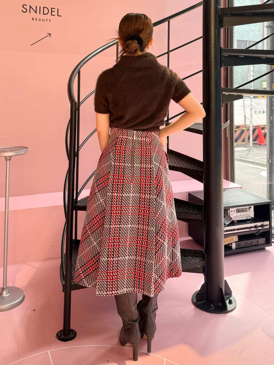 ブラウン系のニット/セーター、レッド系のスカート、ブラウン系のブーツを着用したレディースの秋コーディネートの2枚目の写真