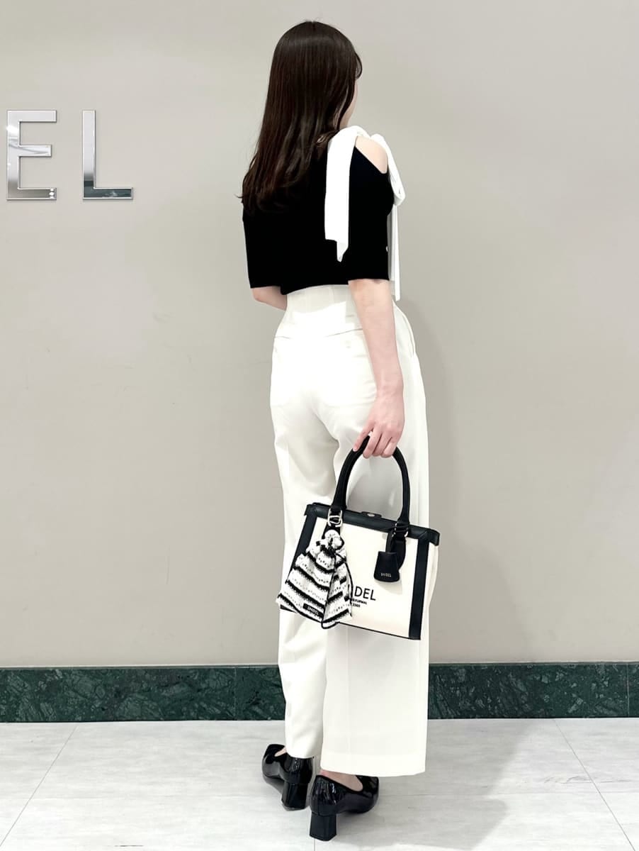 ホワイト系のスラックス、ホワイト系のハンドバッグ、ブラック系のパンプスを着用したレディースの春コーディネートの4枚目の写真