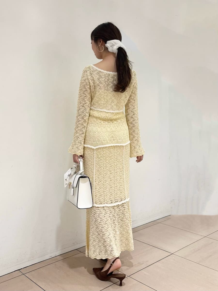 イエロー系のスカート、ブラウン系のパンプス、ホワイト系のハンドバッグを着用したレディースの冬コーディネートの4枚目の写真