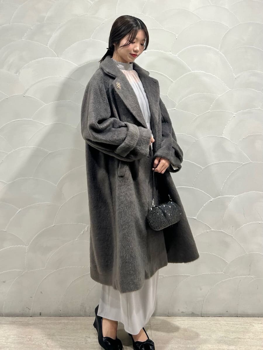 グレー系のチェスターコート、ブルー系のワンピースを着用したレディースの冬コーディネートの2枚目の写真