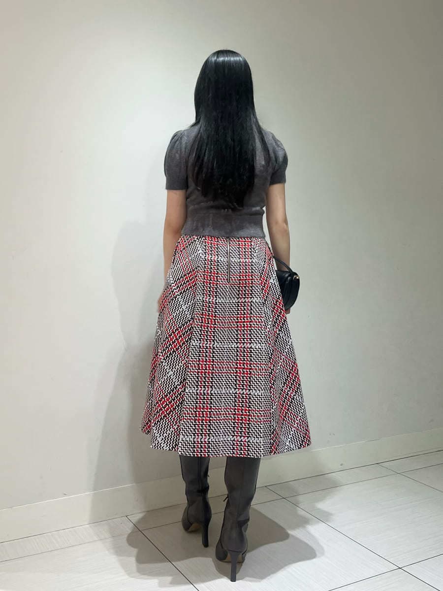 グレー系のニット/セーター、レッド系のスカート、ブラック系のハンドバッグを着用したレディースの秋コーディネートの3枚目の写真