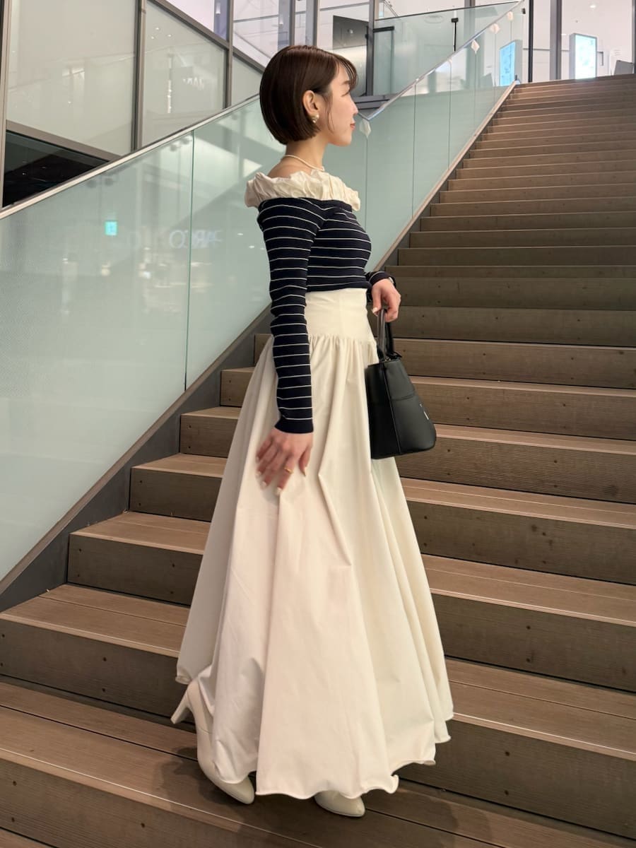 ベージュ系のトレンチコート、ホワイト系のスカート、その他のニット/セーターを着用したレディースの冬コーディネートの4枚目の写真