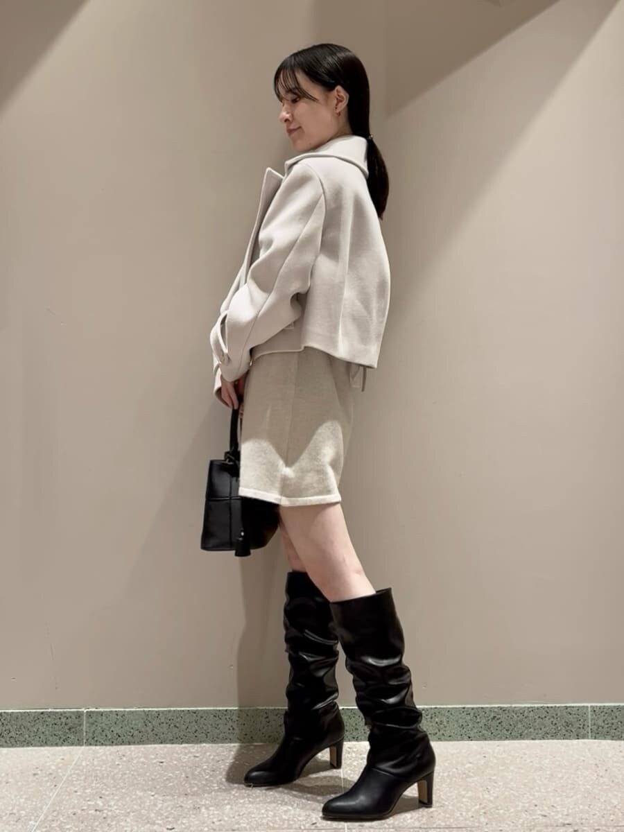 ホワイト系のワンピース、ベージュ系のピーコート、ブラック系のハンドバッグを着用したレディースの冬コーディネートの2枚目の写真