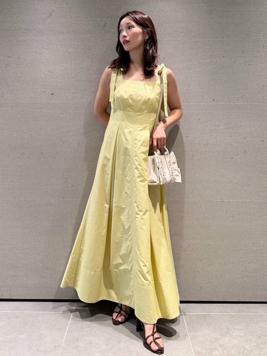 イエロー系のワンピース、ベージュ系のショルダーバッグ、ブラウン系のサンダルを着用したレディースの夏コーディネートの5枚目の写真