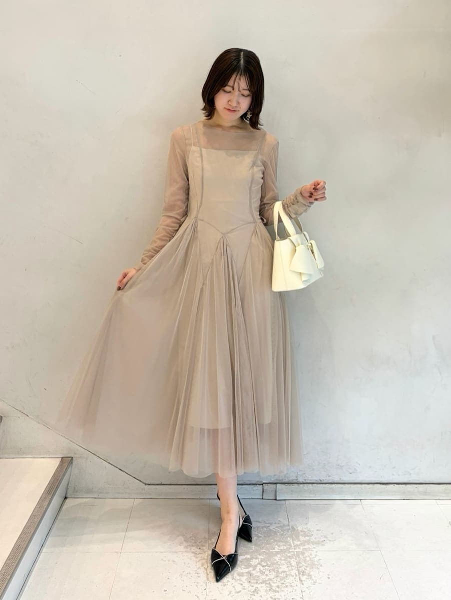 グレー系のドレス、ブラック系のパンプス、ホワイト系のハンドバッグを着用したレディースの冬コーディネートの3枚目の写真