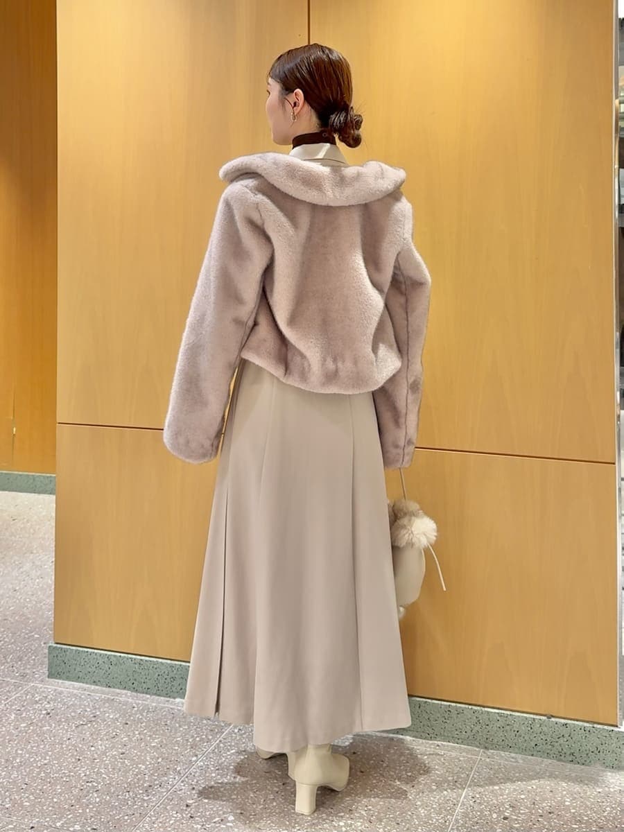 ピンク系のステンカラーコート、ベージュ系のワンピース、ブラウン系のニット/セーターを着用したレディースの秋コーディネートの3枚目の写真
