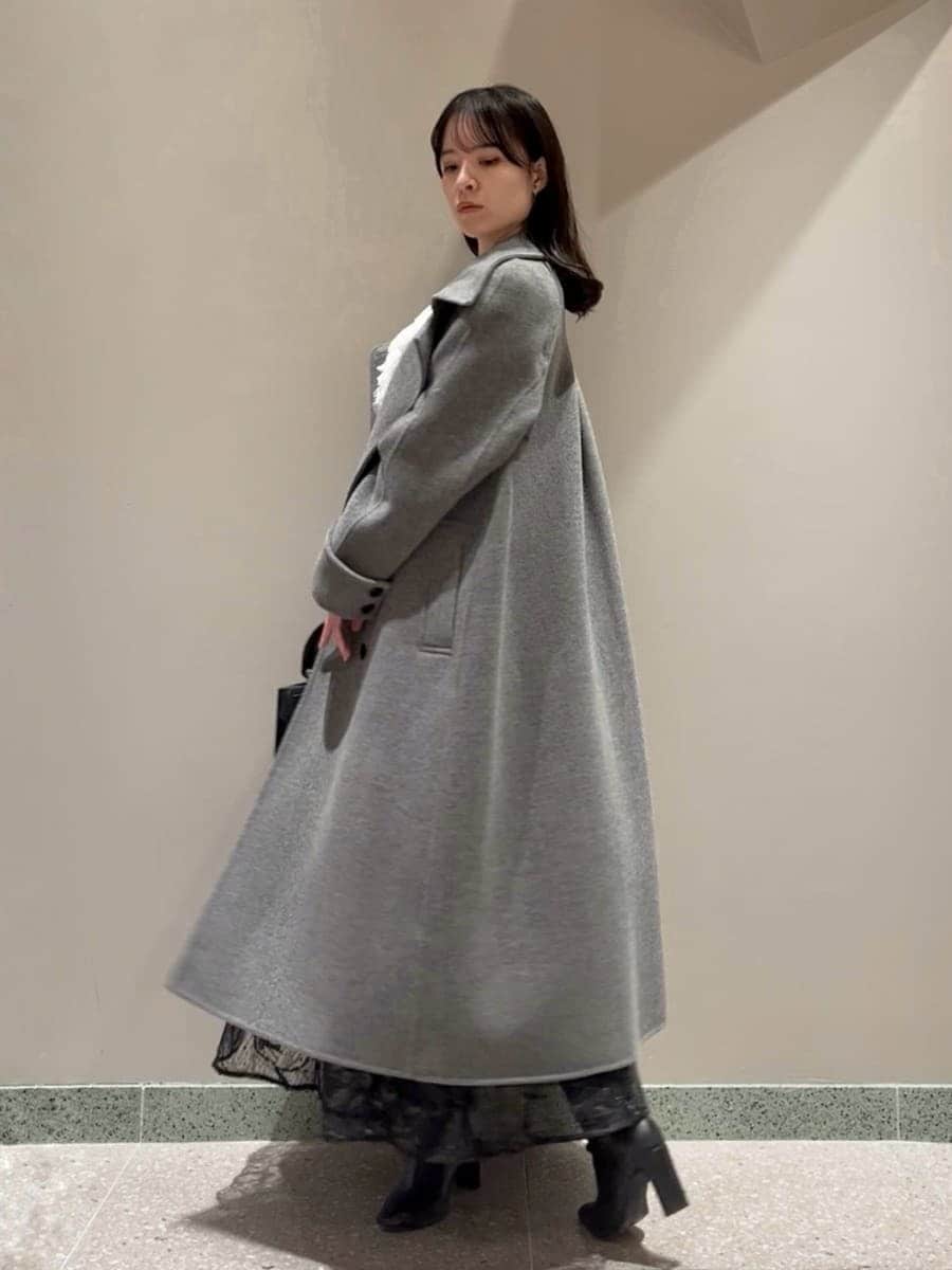 ブラック系のブーツ、グレー系のチェスターコート、ブラック系のスカートを着用したレディースの冬コーディネートの2枚目の写真