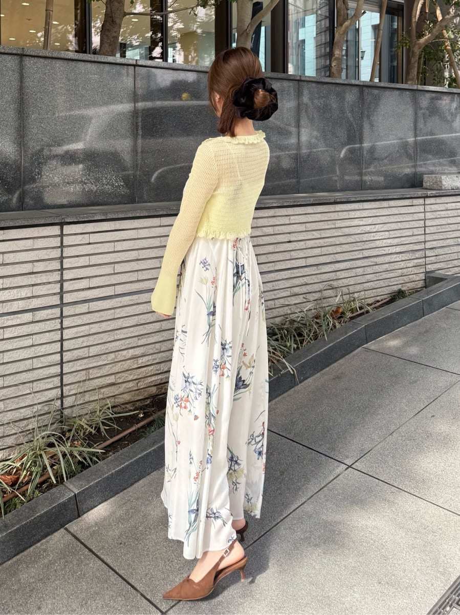 イエロー系のカーディガン/ボレロ、ホワイト系のワンピース、ブラウン系のパンプスを着用したレディースの冬コーディネートの2枚目の写真