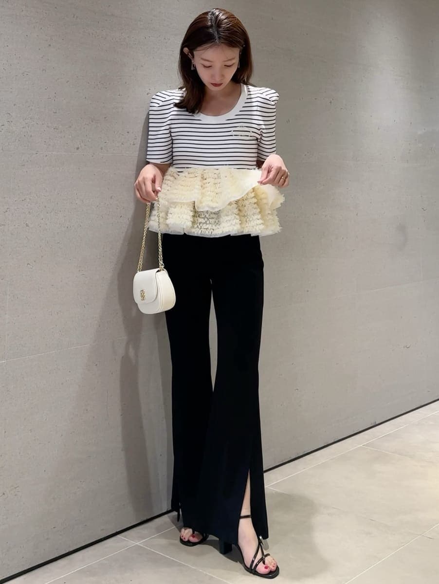 ブラック系のその他パンツ、その他のニット/セーター、ホワイト系のショルダーバッグを着用したレディースの春コーディネートの6枚目の写真