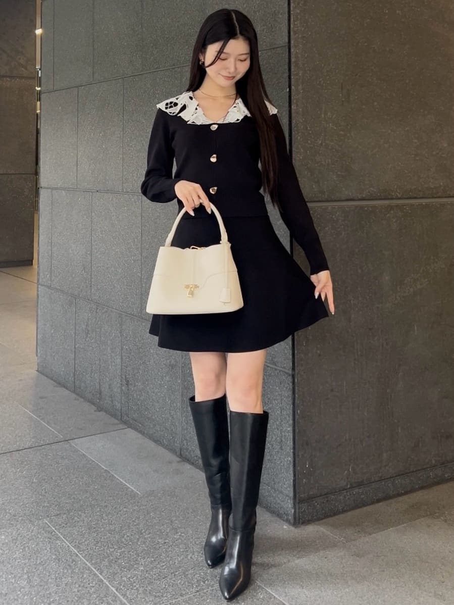 ブラック系のブーツ、ブラック系のワンピース、ホワイト系のハンドバッグを着用したレディースの冬コーディネートの3枚目の写真
