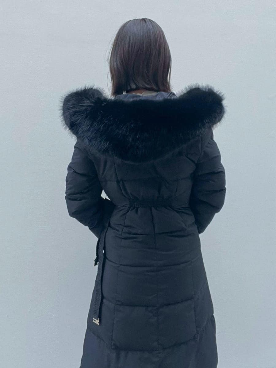 ホワイト系のスカート、ブラック系のブーツ、ブラック系のダウンジャケット/コートを着用したレディースの冬コーディネートの5枚目の写真