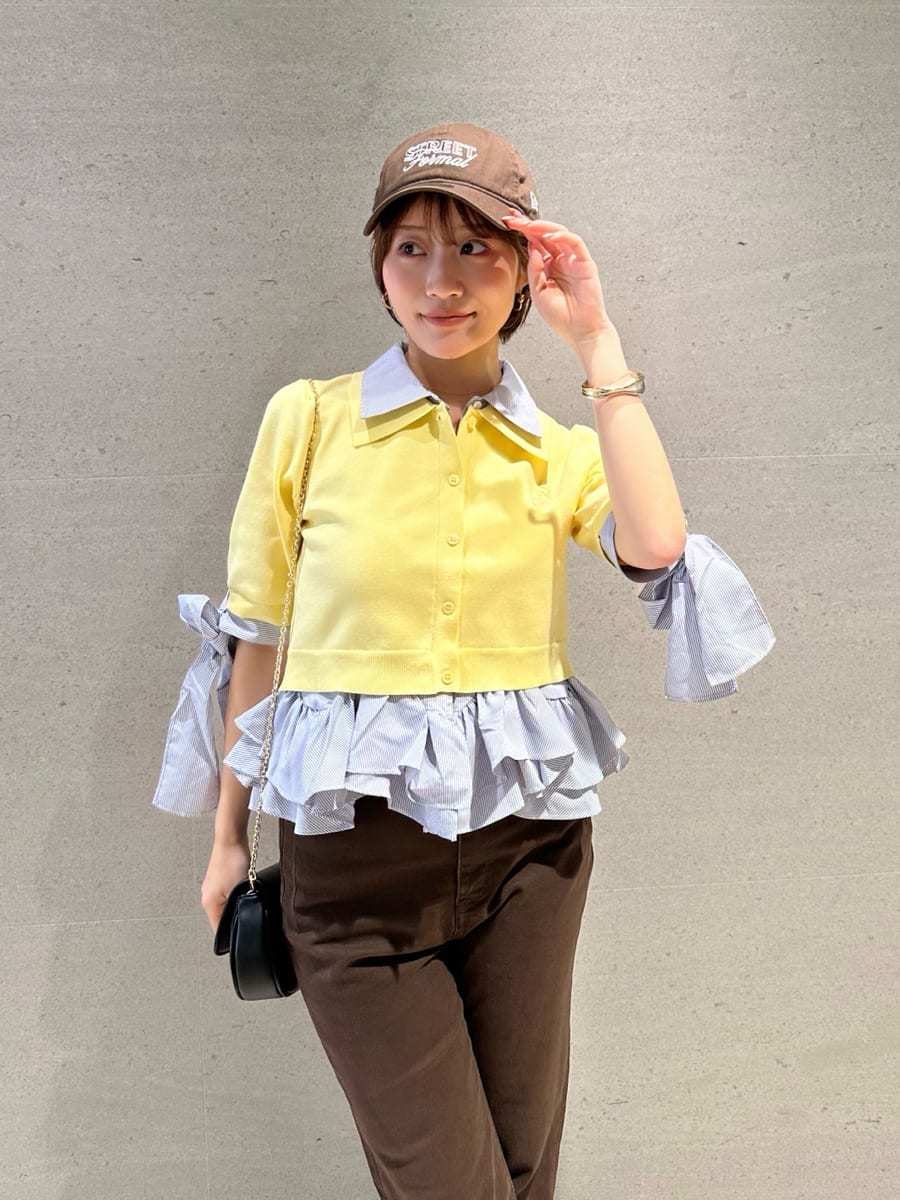 ブラック系のショルダーバッグ、ブラウン系のデニムパンツ、イエロー系のニット/セーターを着用したレディースの春コーディネートの3枚目の写真