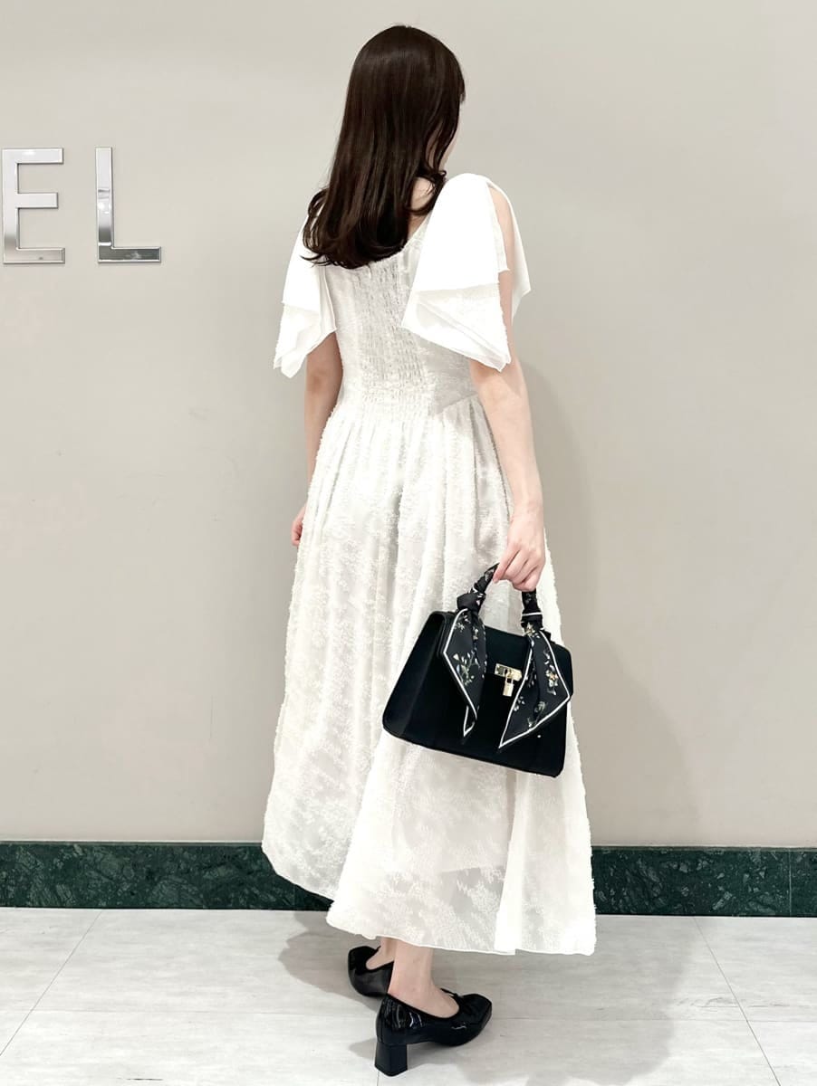 ホワイト系のワンピース、ブラック系のハンドバッグ、ブラック系のパンプスを着用したレディースの春コーディネートの4枚目の写真