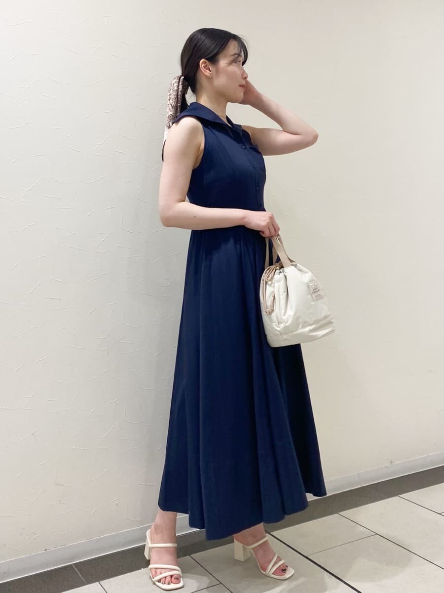 ブルー系のワンピース、ベージュ系のハンドバッグ、ホワイト系のパンプスを着用したレディースの夏コーディネートの2枚目の写真