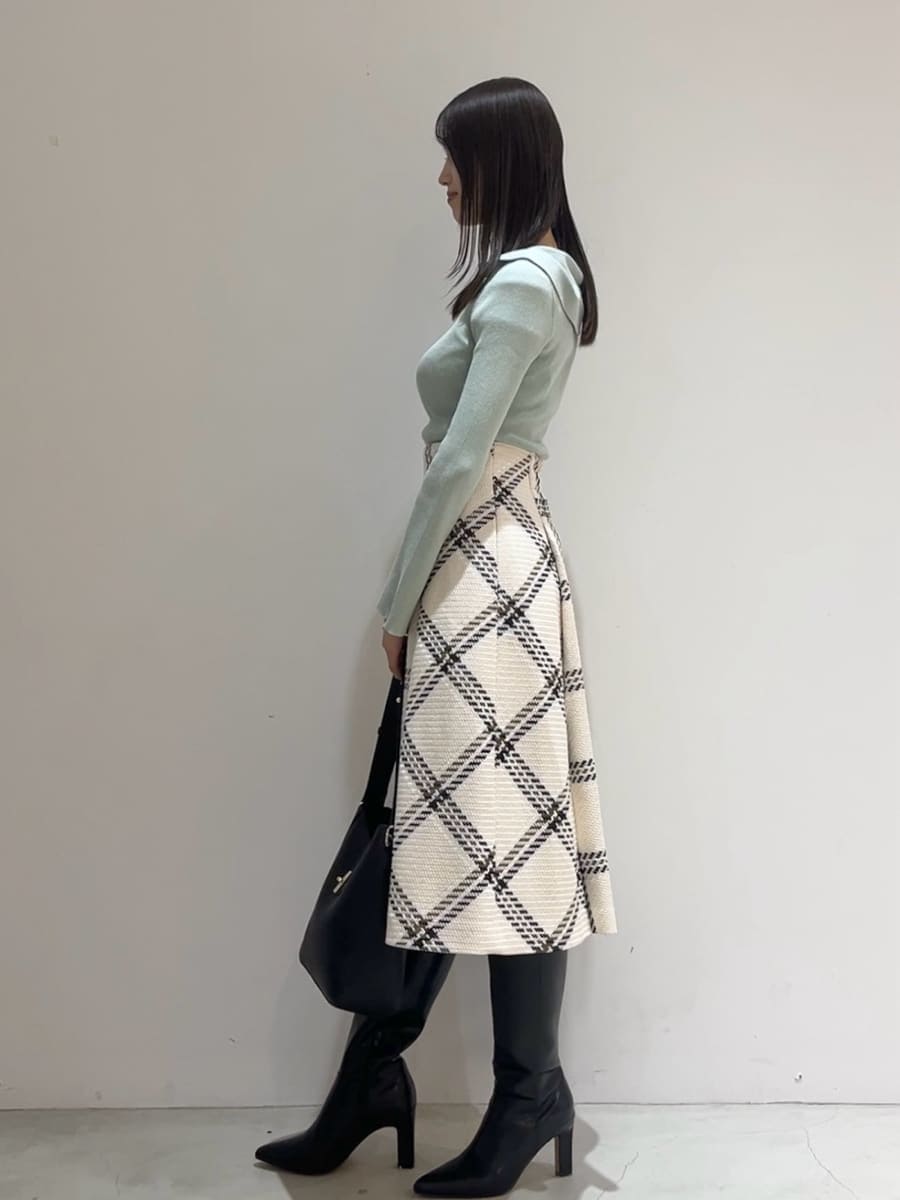 グリーン系のニット/セーター、ホワイト系のスカート、ブラック系のブーツを着用したレディースの秋コーディネートの5枚目の写真
