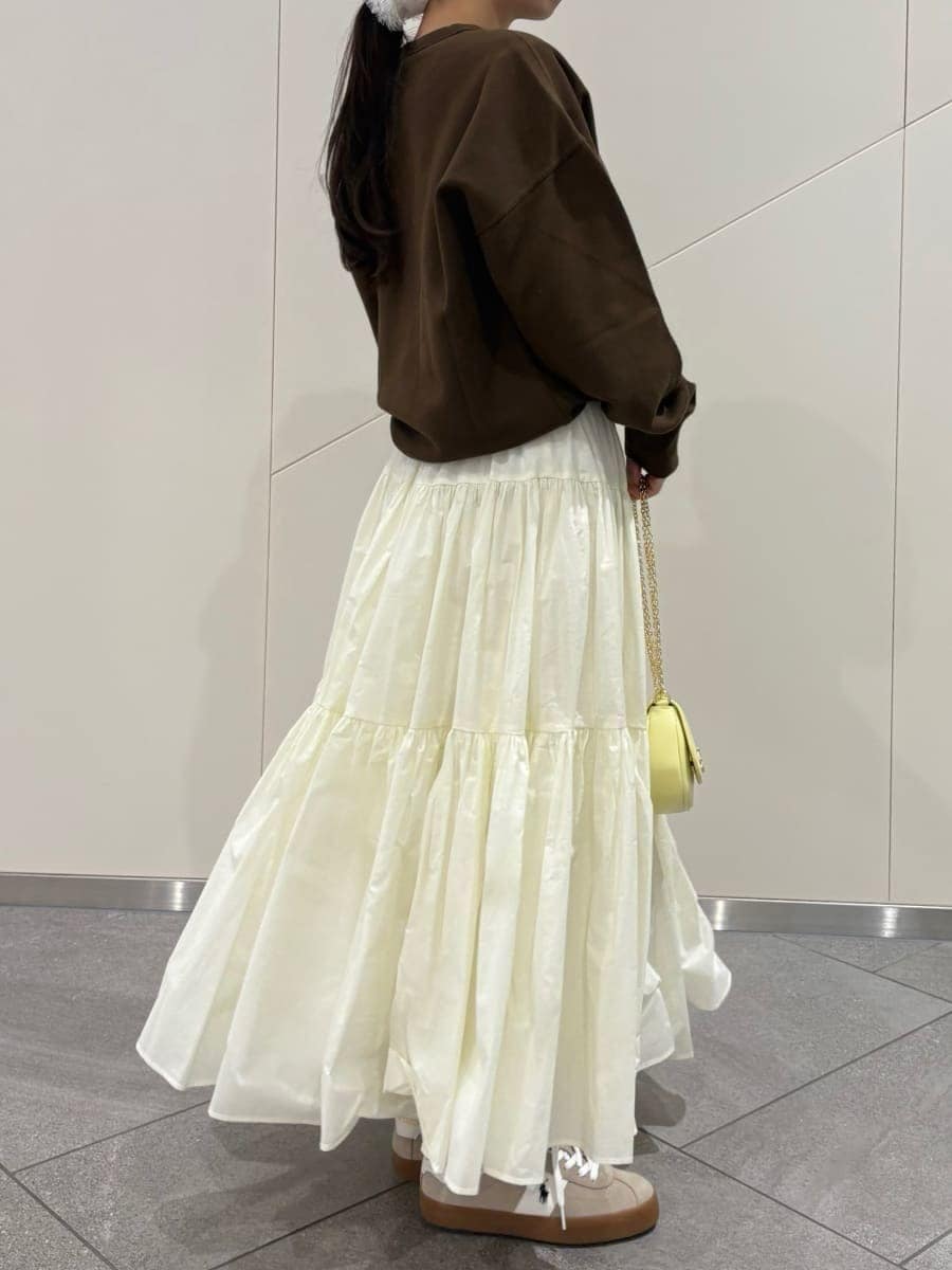 ホワイト系のスカート、ブラウン系のスウェット、イエロー系のショルダーバッグを着用したレディースの春コーディネートの5枚目の写真