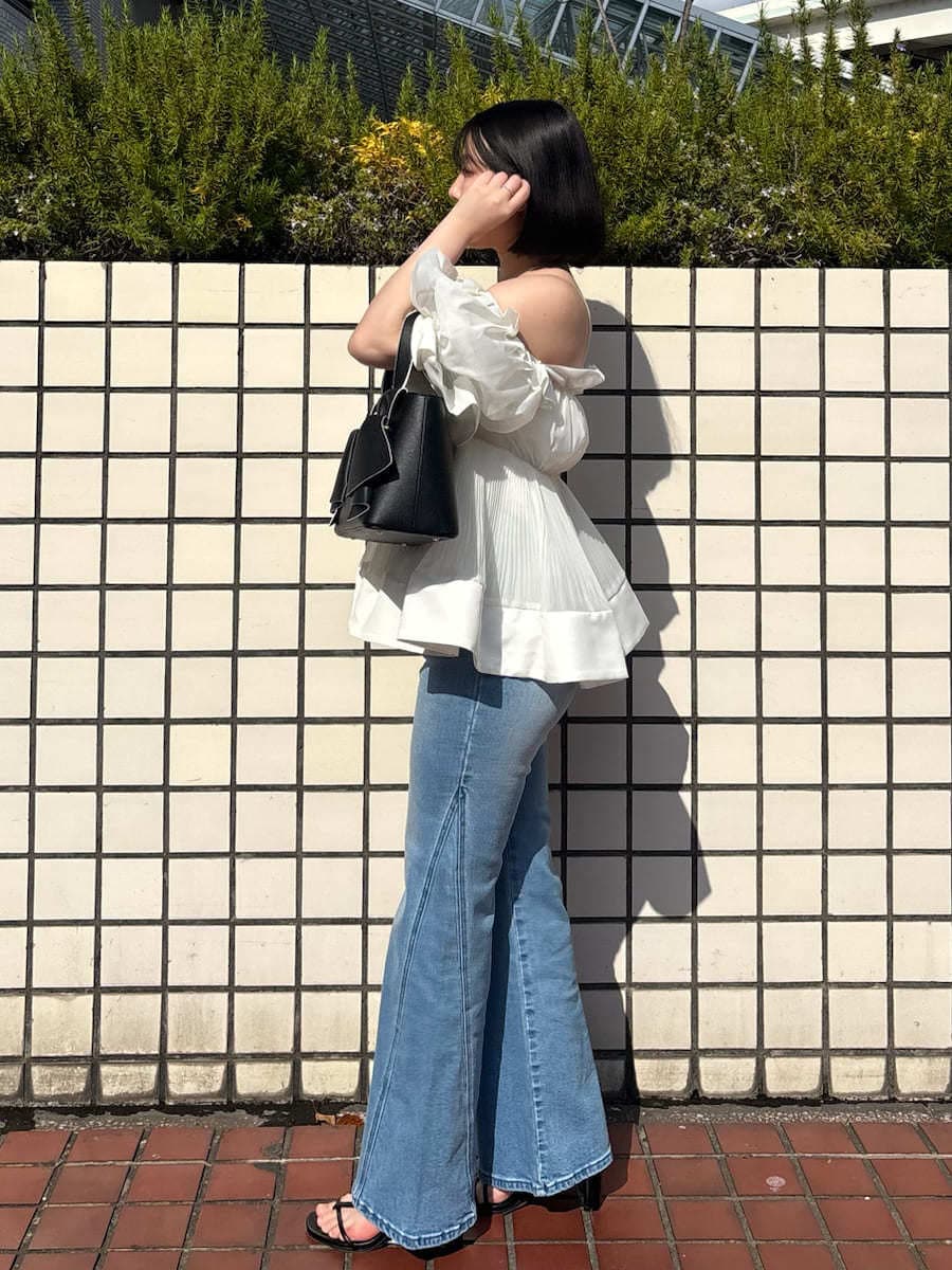 ブルー系のデニムパンツ、ホワイト系のその他トップス、ブラック系のハンドバッグを着用したレディースの春コーディネートの4枚目の写真