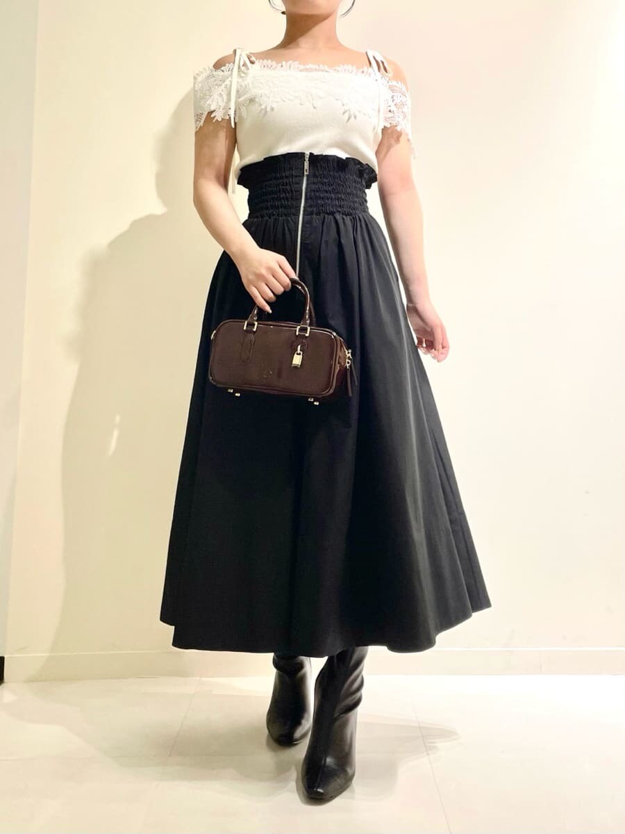 ホワイト系のニット/セーター、ブラック系のスカート、ブラウン系のボストンバッグを着用したレディースの秋コーディネートの2枚目の写真