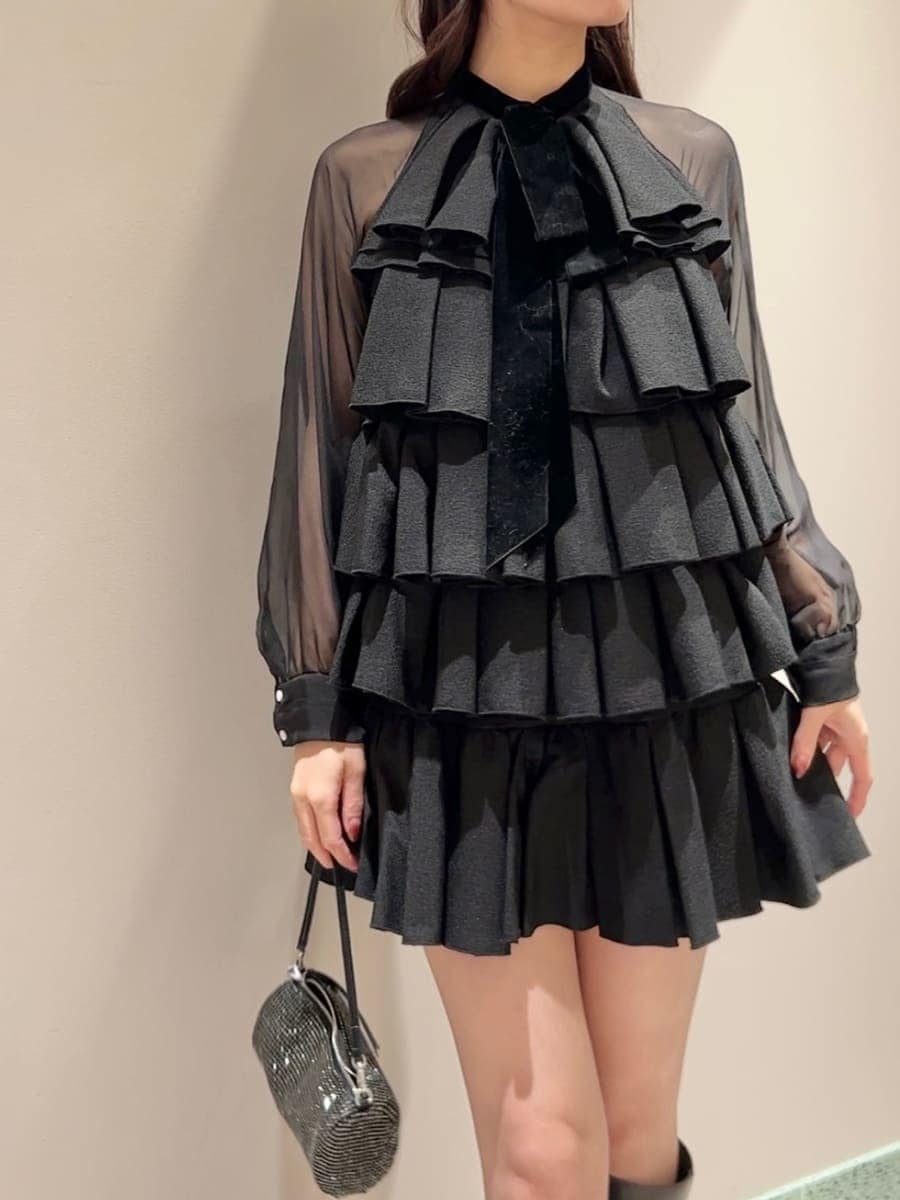 グレー系のブーツ、グレー系のチェスターコート、ブラック系のドレスを着用したレディースの冬コーディネートの6枚目の写真