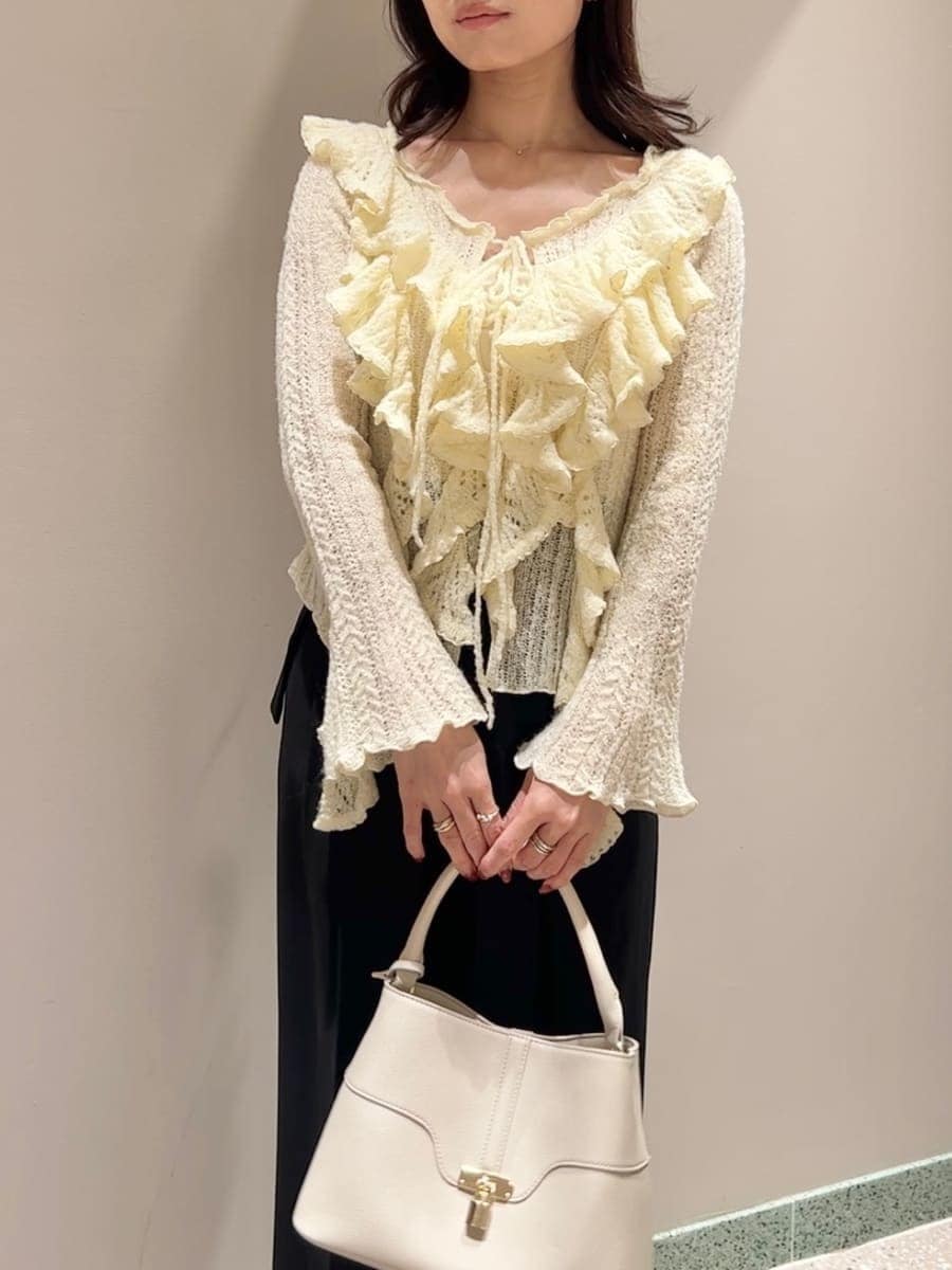 イエロー系のニット/セーター、ホワイト系のハンドバッグを着用したレディースの冬コーディネートの3枚目の写真