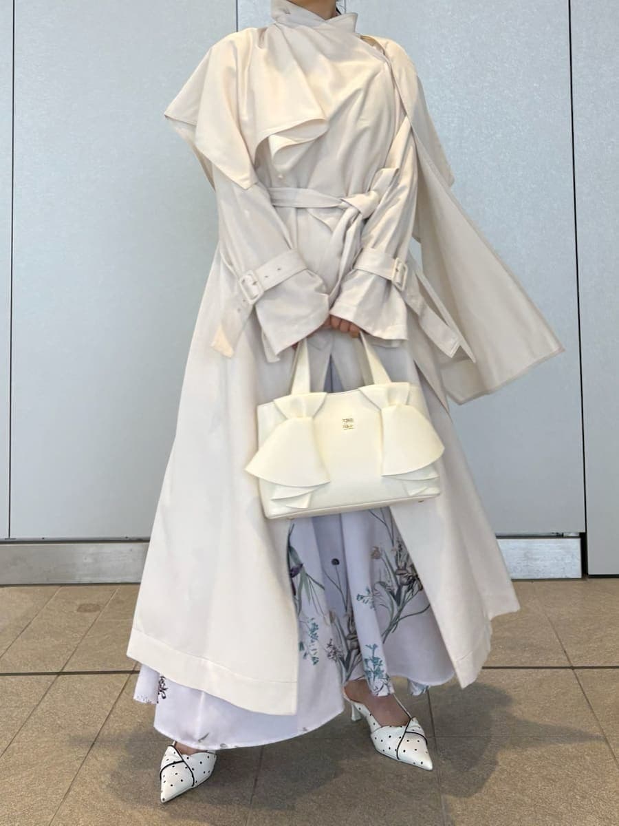 ホワイト系のトレンチコート、パープル系のワンピース、その他のパンプスを着用したレディースの冬コーディネートの7枚目の写真