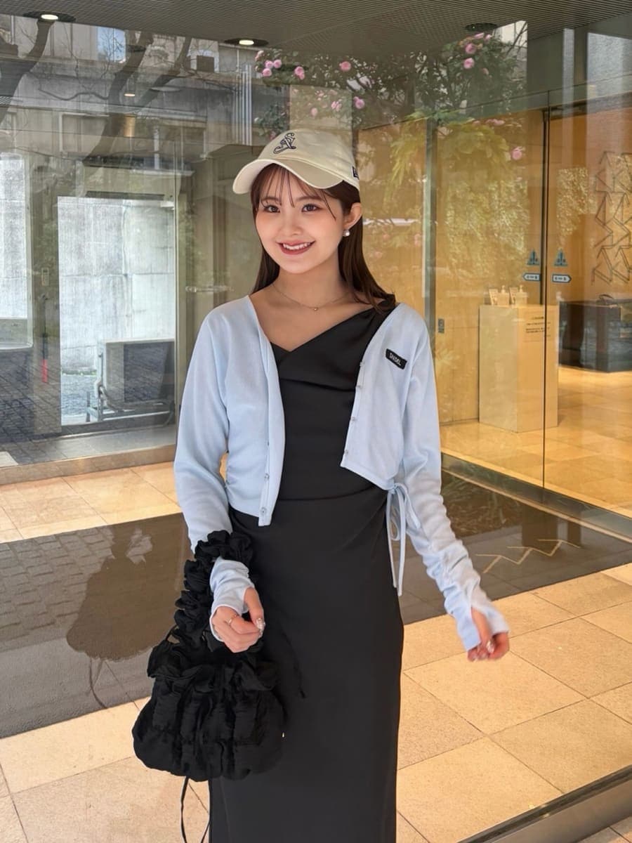 ブラック系のワンピース、ブルー系のカーディガン/ボレロ、ホワイト系のキャップを着用したレディースの春コーディネートの3枚目の写真