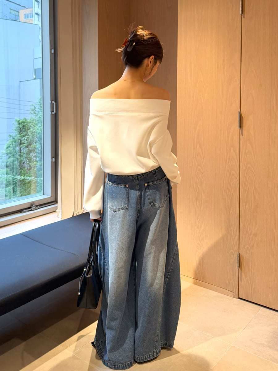 ブルー系のデニムパンツ、ホワイト系のワンピース、ブラック系のボストンバッグを着用したレディースの秋コーディネートの4枚目の写真
