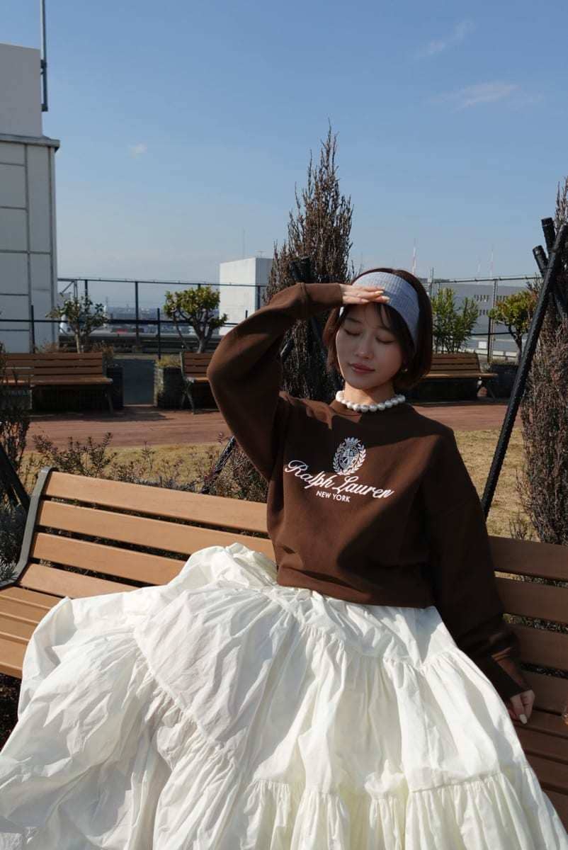 ホワイト系のスカート、ブラウン系のスウェット、ベージュ系のスニーカーを着用したレディースの春コーディネートの3枚目の写真