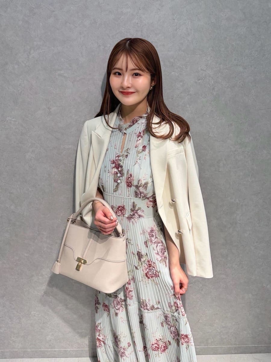 ホワイト系のテーラードジャケット、グリーン系のワンピース、ベージュ系のハンドバッグを着用したレディースの春コーディネートの2枚目の写真