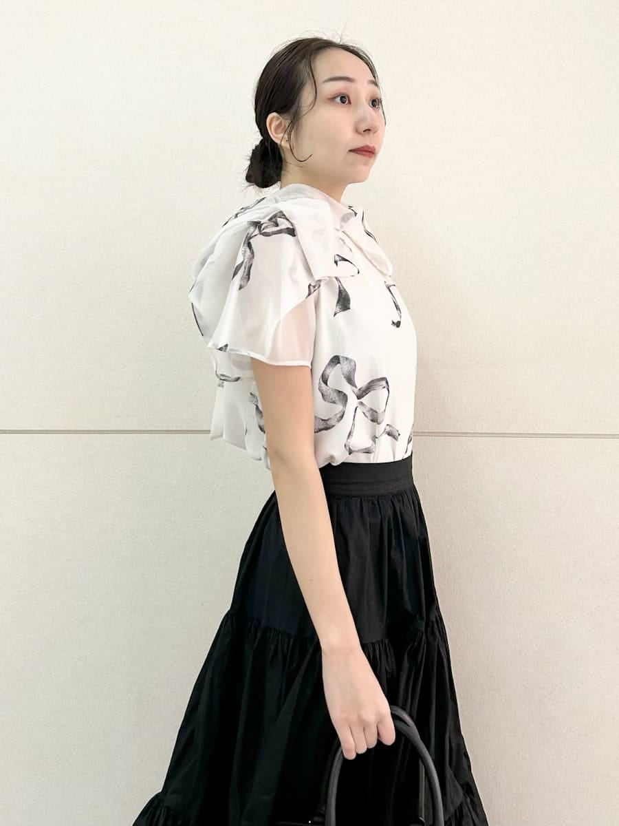 ブラック系のスカート、ブラック系のパンプス、ホワイト系のハンドバッグを着用したレディースの春コーディネートの6枚目の写真