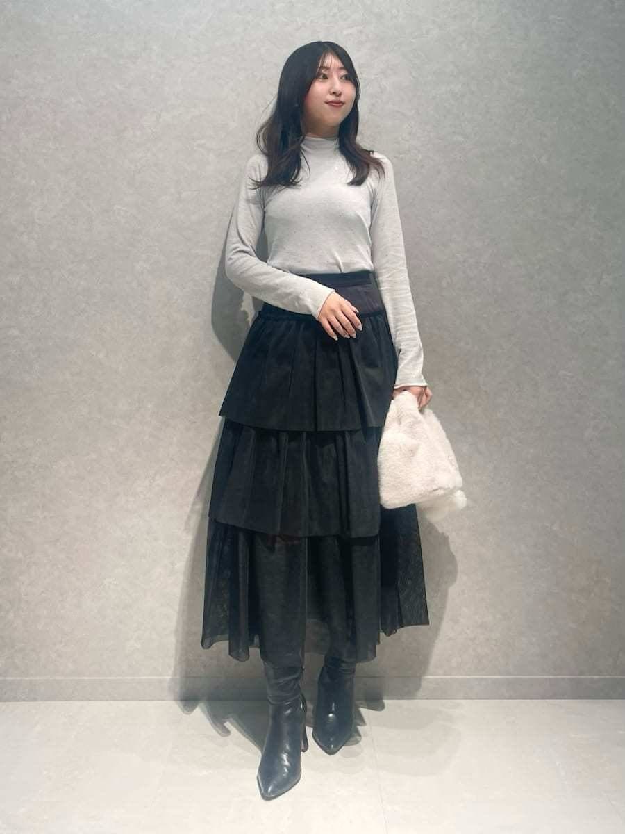 ブラック系のブーツ、グレー系のチェスターコート、ブラック系のスカートを着用したレディースの冬コーディネートの2枚目の写真