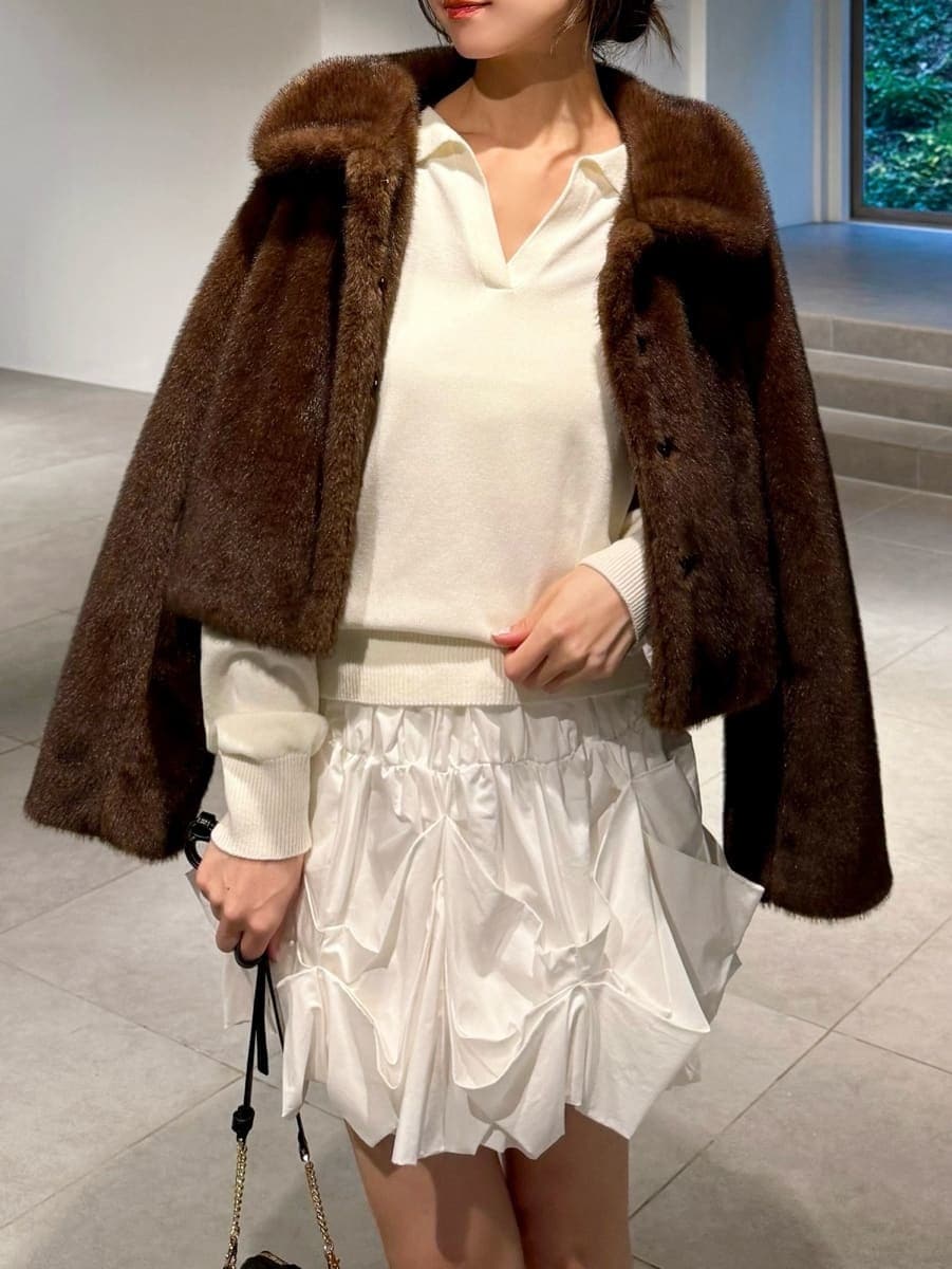 ホワイト系のキャミソール、ブラック系のブーツ、ブラウン系のステンカラーコートを着用したレディースの秋コーディネートの5枚目の写真