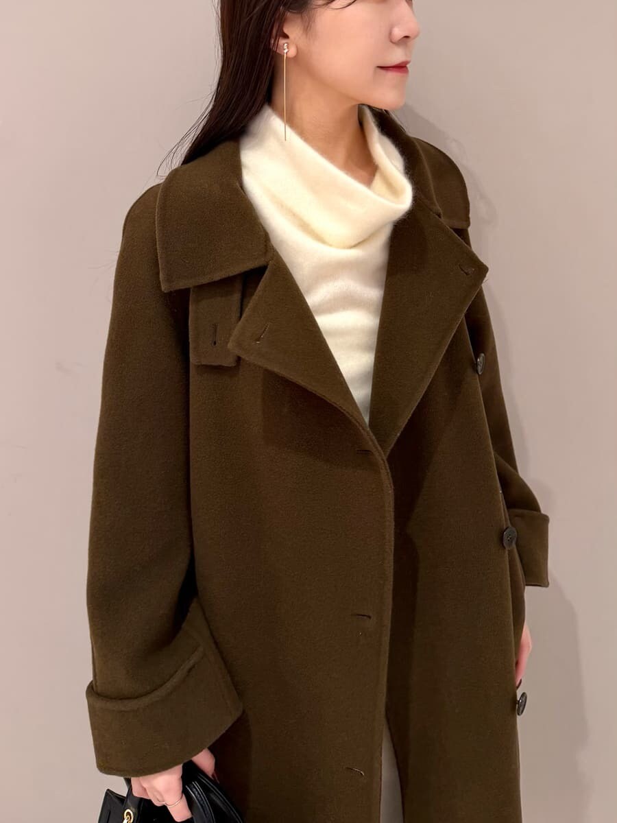 ホワイト系のワンピース、ブラック系のハンドバッグ、ブラウン系のチェスターコートを着用したレディースの冬コーディネートの4枚目の写真