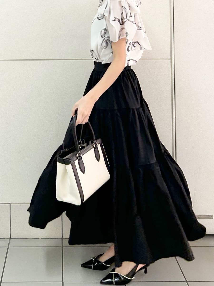 ブラック系のスカート、ブラック系のパンプス、ホワイト系のハンドバッグを着用したレディースの春コーディネートの3枚目の写真