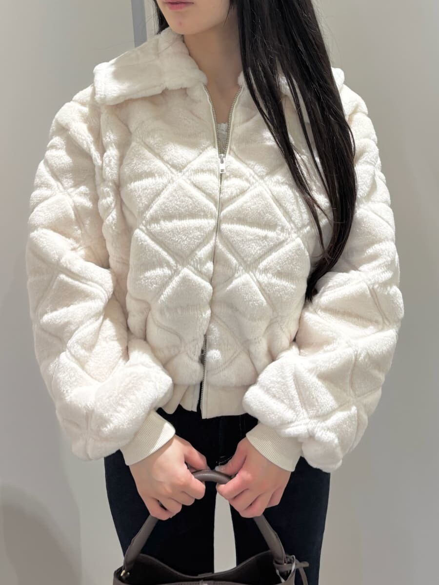 ブラウン系のハンドバッグ、ブルー系のデニムパンツ、ホワイト系のブルゾンを着用したレディースの秋コーディネートの5枚目の写真