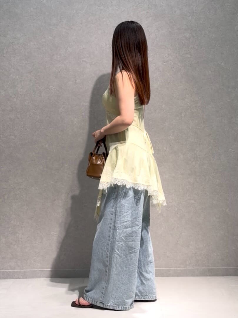 ブルー系のデニムパンツ、ブラウン系のボストンバッグ、イエロー系のキャミソールを着用したレディースの夏コーディネートの3枚目の写真