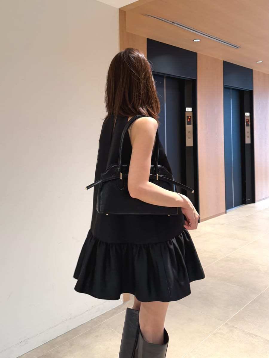 グレー系のブーツ、ブラック系のワンピース、ブラック系のボストンバッグを着用したレディースの秋コーディネートの3枚目の写真