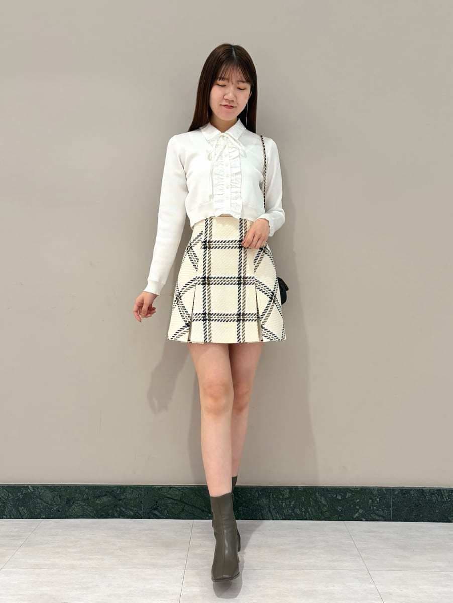 ホワイト系のスカート、ブラック系のショルダーバッグ、ホワイト系のカーディガン/ボレロを着用したレディースの冬コーディネートの2枚目の写真