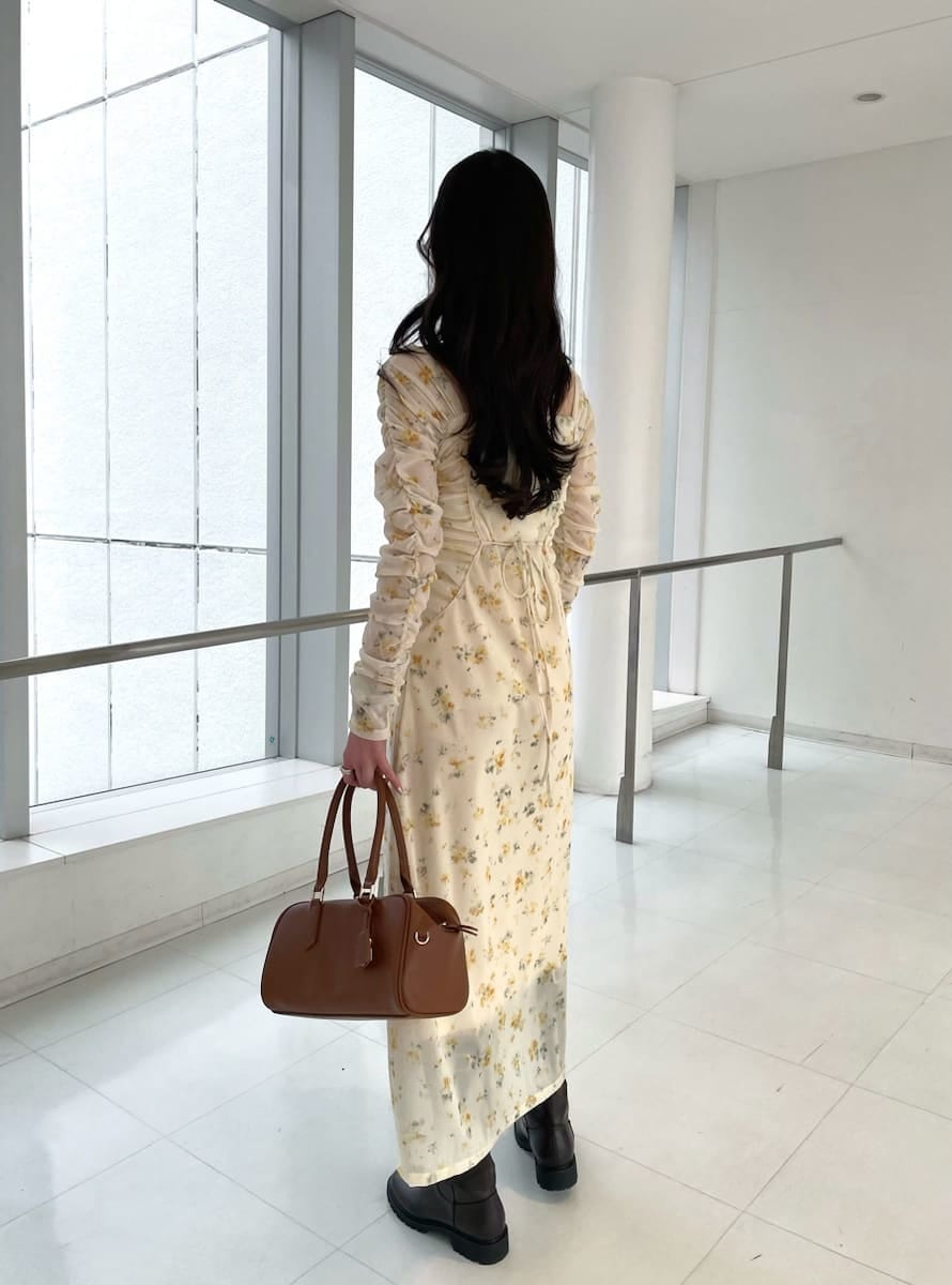 イエロー系のワンピース、ベージュ系のトレンチコート、イエロー系のボストンバッグを着用したレディースの冬コーディネートの5枚目の写真