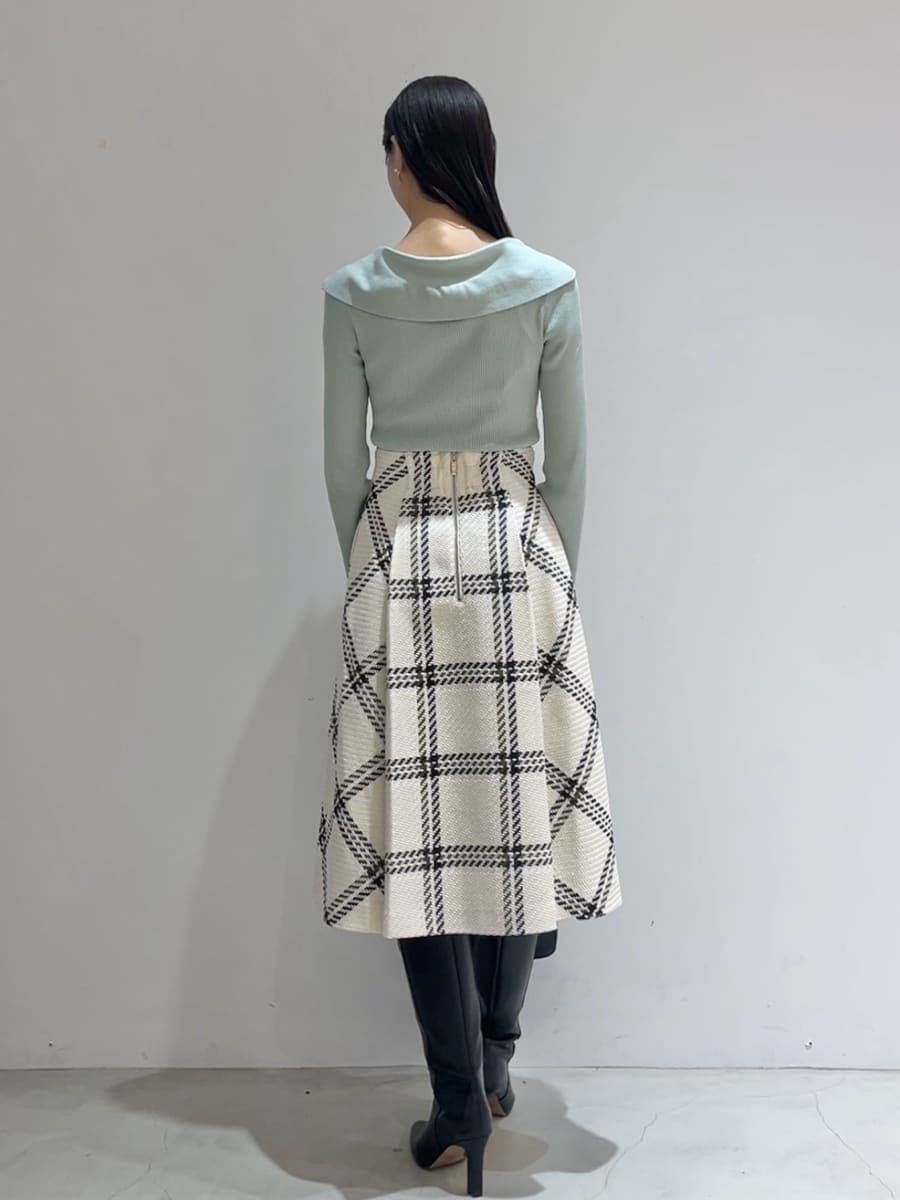 グリーン系のニット/セーター、ホワイト系のスカート、ブラック系のブーツを着用したレディースの秋コーディネートの8枚目の写真