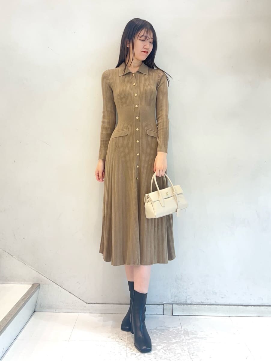 ホワイト系のチェスターコート、ベージュ系のワンピース、ホワイト系のボストンバッグを着用したレディースの秋コーディネートの7枚目の写真