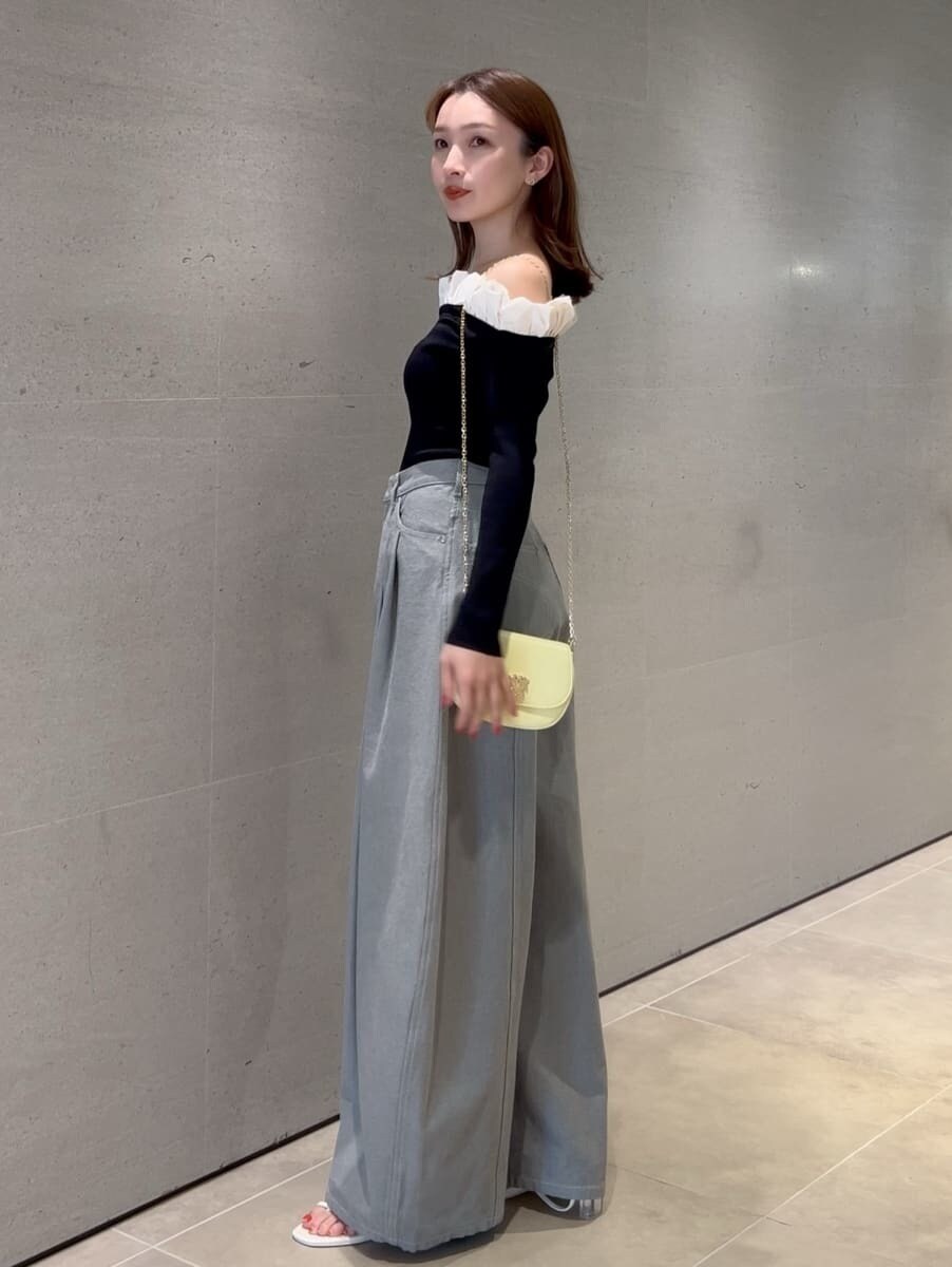 グレー系のデニムパンツ、ブラック系のニット/セーター、イエロー系のショルダーバッグを着用したレディースの冬コーディネートの2枚目の写真