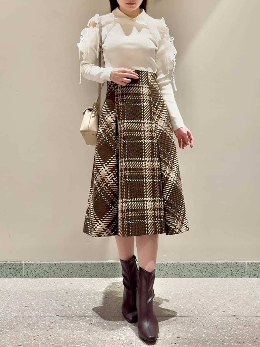 ホワイト系のニット/セーター、ブラウン系のスカート、レッド系のブーツを着用したレディースの秋コーディネートの6枚目の写真