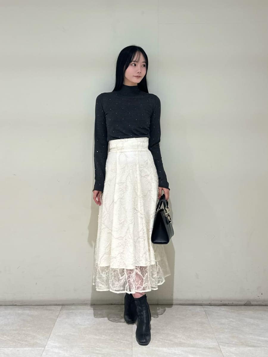 ホワイト系のスカート、グレー系のニット/セーター、ブラック系のハンドバッグを着用したレディースの秋コーディネートの5枚目の写真